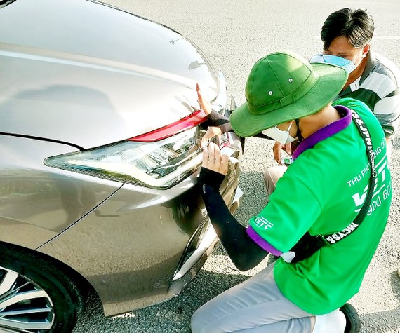 Nhiều tài xế phải dừng xe trên đường cao tốc để dán thẻ  thu phí tự động. Ảnh: HOÀNG BẮC