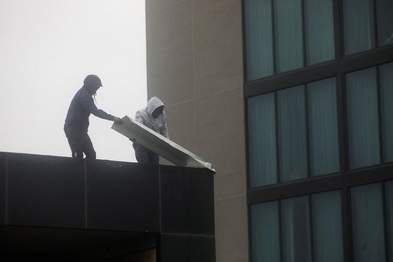 Hai người đàn ông đang gia cố nhà cửa. Ảnh: Reuters