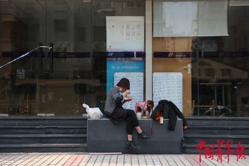 Người phụ nữ và chó cưng dùng bữa trước cửa một trung tâm môi giới nhà đất ở quận Hoàng Phố, ngày 3/5. Ảnh: China Youth Daily